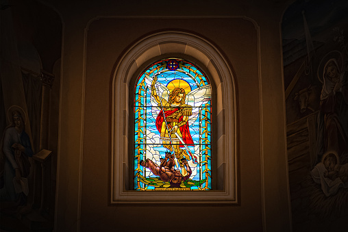 stained glass window with saint michael who kills a demon