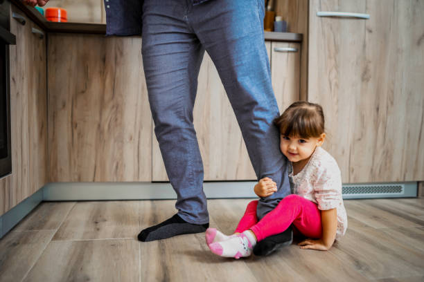 istock Lovely daughter playing with her father's leg in the kitchen 1357928510