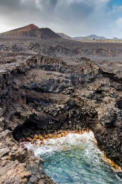 Landscape of old lava streams at Fuencaliente, La Palma with sea foreground. Volcano in the background.