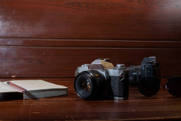 istock Two antique cameras next to a book and a pencil on a coffee table. 1357928653