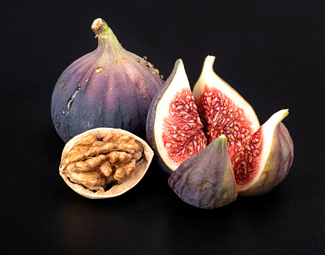 Whole figs and chopped and split walnuts isolated on a black background