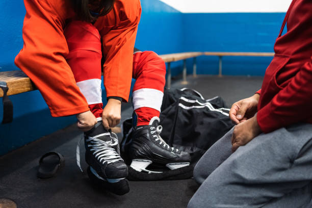 vater hilft seinem sohn, sich auf das training vorzubereiten - ice skating ice hockey child family stock-fotos und bilder