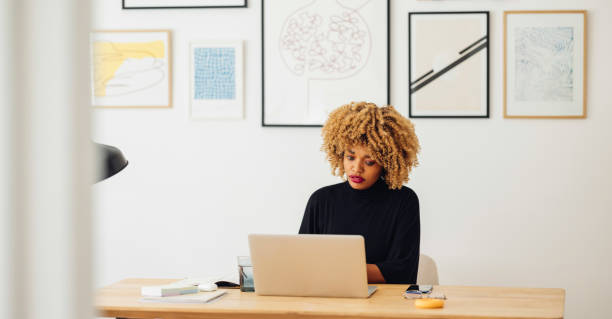 istock Beautiful African American Woman Using her Laptop While Working from Home 1357935444