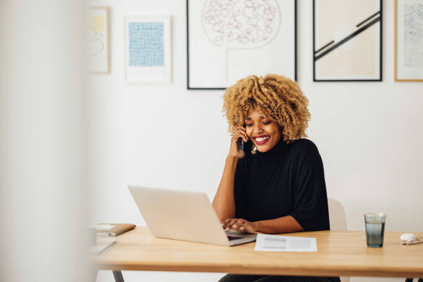 istock Cheerful Businesswoman Talking on the Phone While Using her Laptop 1357935485