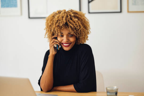 istock Cheerful Businesswoman Talking on the Phone While Using her Laptop 1357935498