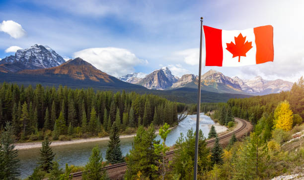 Canadian National Flag composite with Rocky Mountain Landscape in background. Canadian National Flag composite with Rocky Mountain Landscape in background. Fall Season Sunny Sky. Lake Louise, Banff National Park, Alberta, Canada. rocky mountains banff alberta mountain stock pictures, royalty-free photos & images