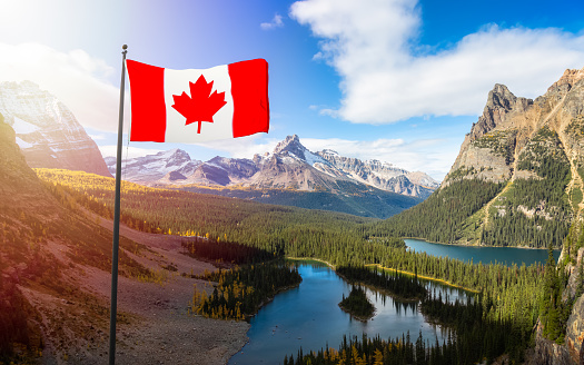 Canadian National Flag Composite with Canadian Rocky Mountains in Background. Sunny Fall Day. Located in Lake O'Hara, Yoho National Park, British Columbia, Canada.