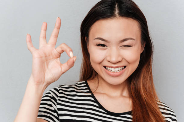 istock Winking young woman showing ok gesture 1357940712