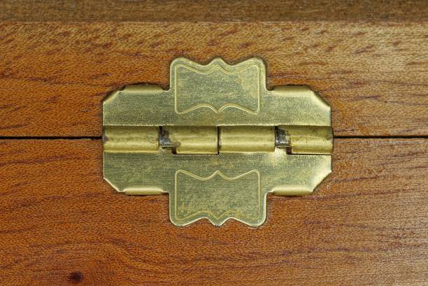 one small yellow brass hinge on a brown wooden box board