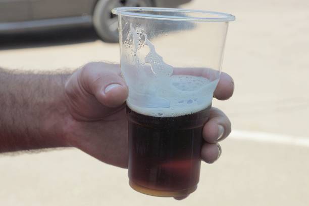 istock a man hand holds a large white plastic glass with a red drink 1357942149