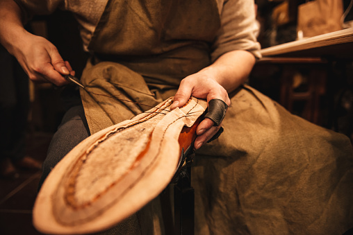 Cropped photo of young man shoemaker at footwear workshop.