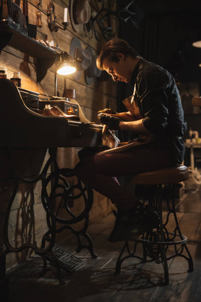 istock Concentrated man shoemaker at footwear workshop. 1357947164