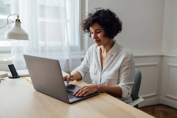 una bella donna afro-americana che lavora online sul suo laptop - donne di età media foto e immagini stock