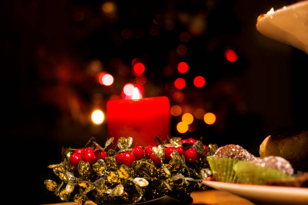 Candle, lights, wreath and Christmas cookies on the table.