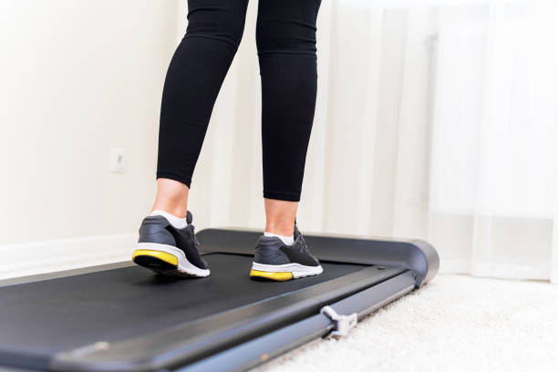 istock Sporty woman using walking treadmill on white background 1357950969