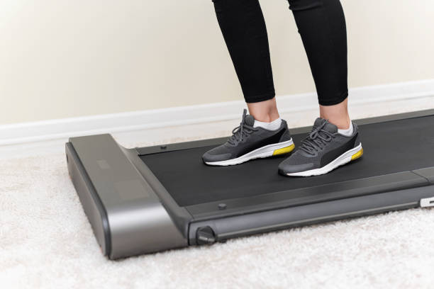 istock Sporty woman using walking treadmill on white background 1357950975