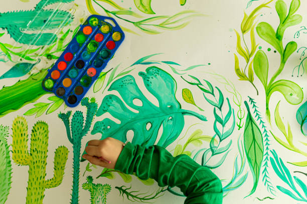 istock Unrecognizable girl, using watercolor paints to paint plants 1357954190