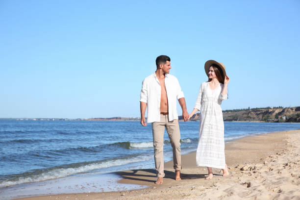istock Lovely couple walking on beach. Space for text 1357954338