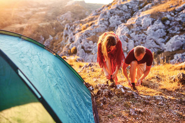 istock Young couple tying shoelaces while camping 1357954424