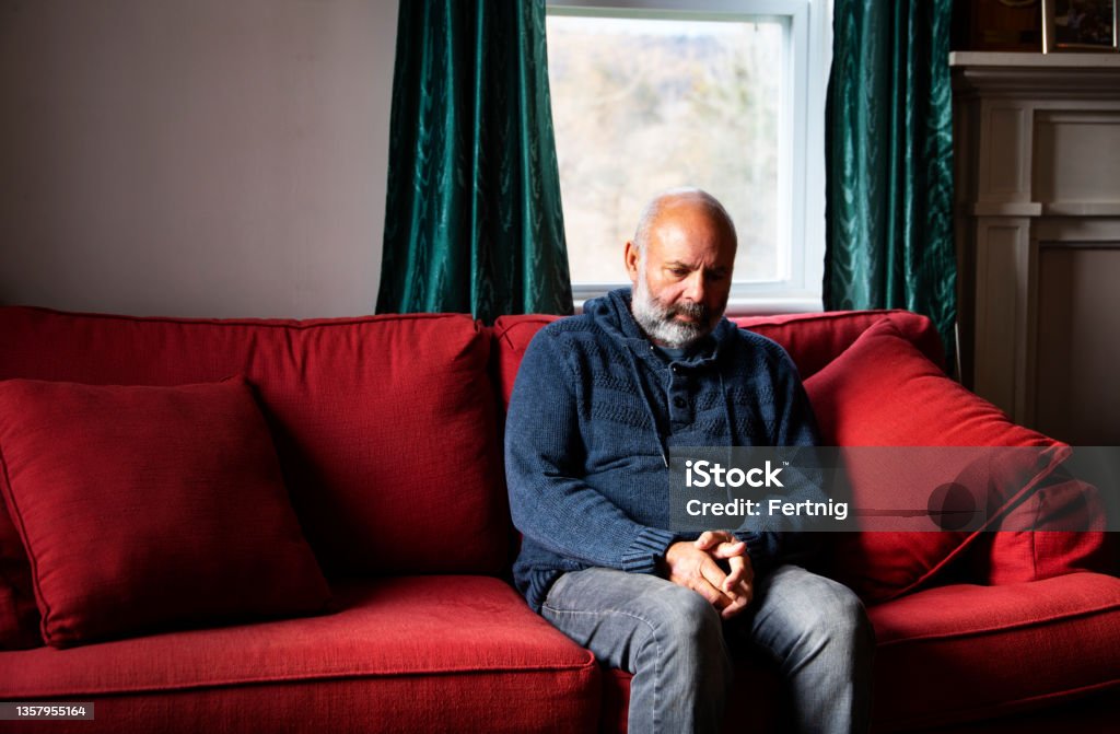 Mental health can affect us all A mature man sitting alone at home dealing with an expression of sadness or anxiety. Photographed in North America. Men Stock Photo