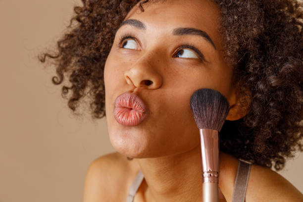 istock Pretty woman holding cosmetic makeup brush in studio 1357956363