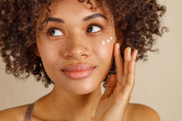 милая дама с использованием косметического продукта в студии - moisturizer beauty treatment human skin applying стоковые фото и изображения