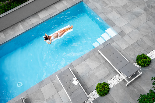 Pregnant woman floating on inflatable mat in the swimming pool