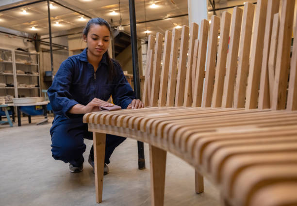 Latin American female carpenter sanding a wood bench at the workshop - carpentry concepts