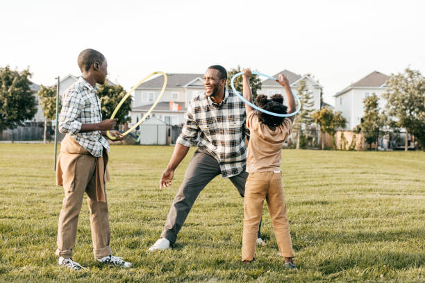 istock Dad and kids playing outside with hula hoops 1357968673