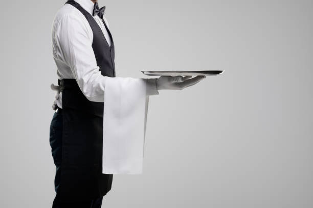 istock Elegant waiter in uniform carrying tray 1357969430