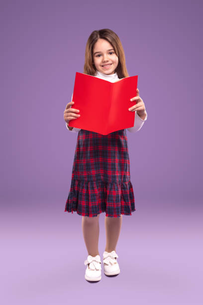 istock Diligent schoolgirl reading textbook and smiling 1357969455