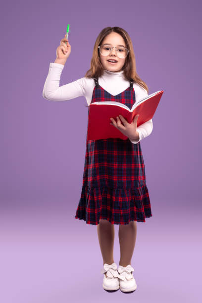 Smart schoolgirl with book and pen stock photo