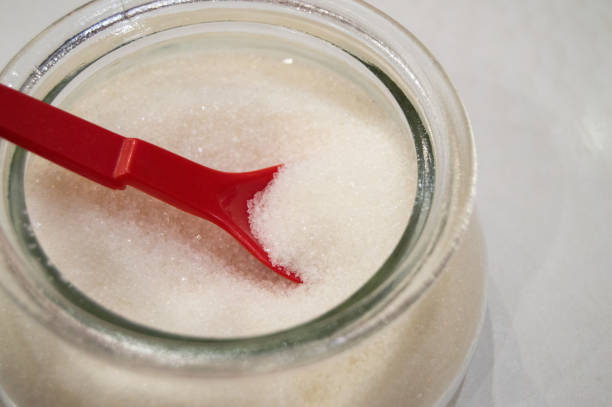 istock Glass sugar bowl with sugar and a red spoon, top view 1357971418