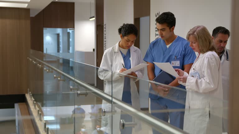 Team of surgeons discussing a case while looking at paperwork in the hospital’s corridor