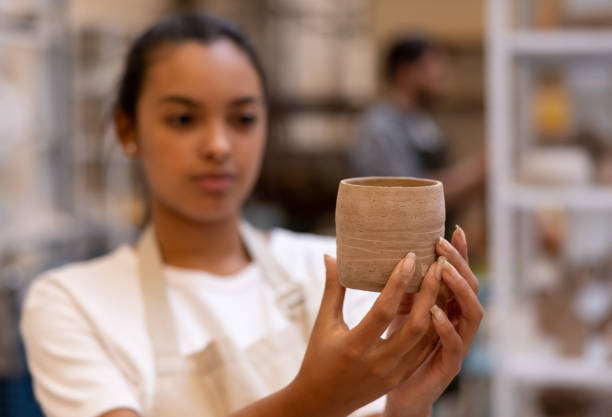 istock Woman in a pottery class looking at a pot she made 1357976522
