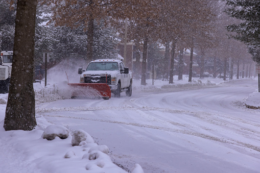 Municipal service with snowplow removing snow from road in after heavy snowfall.