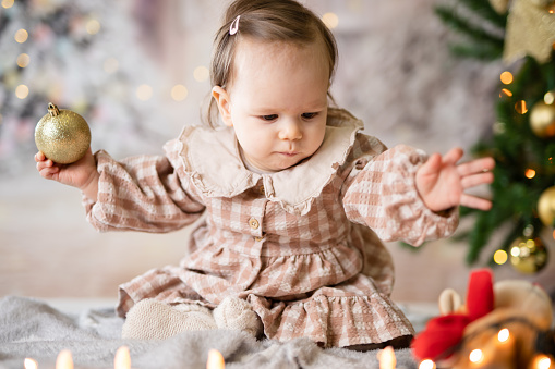 One small caucasian baby girl sitting playing with Christmas decoration