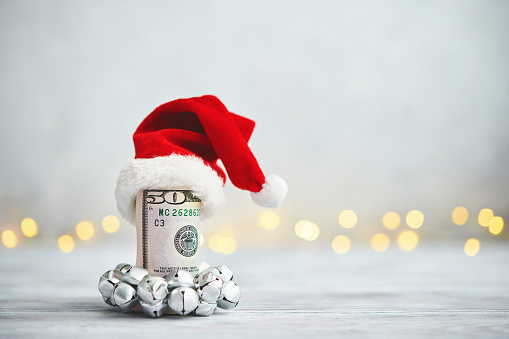 Give the Gift of Cash at Christmas. Holiday Background with Money Roll wearing Santa Hat