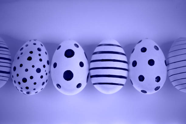 Different graphic hand-painted eggs in Proton Purple neon light. Easter concept. Top view. Demonstrating color of 2022 year