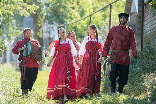 A group of young people in Russian national costumes walking around the village, close up