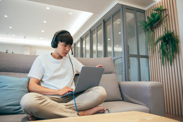 istock Young Asia businessman using laptop talk to colleagues about plan in video call while smart working from home at living room. 1357995184