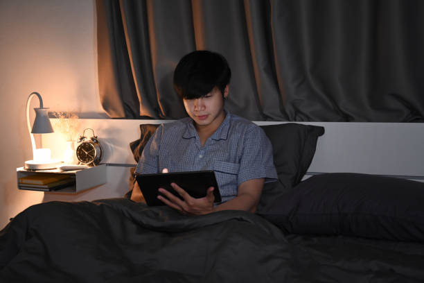 istock Young man in pajamas using digital tablet on his bed. 1357999185