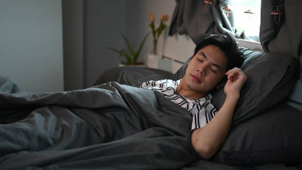 istock Asian man sleeping in his comfortable bed after tiring day. 1357999406
