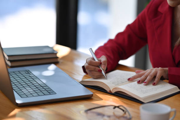 istock Businesswoman using computer laptop and writing information on notebook. 1358000056