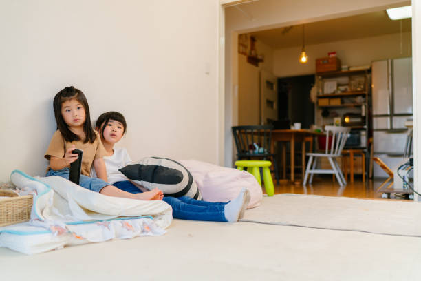 Sisters watching tv together at home Two sisters are watching tv together in the living room at home japan small apartment stock pictures, royalty-free photos & images