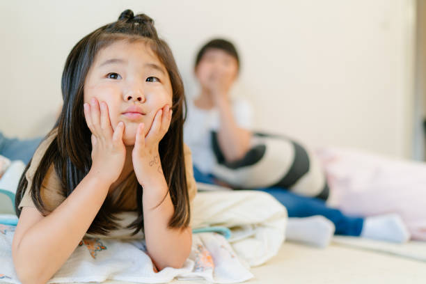 An Asian girl happily lies in bed