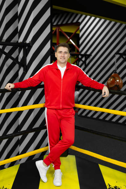 Man in a red tracksuit poses and has fun in the boxing ring Man in a red tracksuit poses and has fun in the boxing ring tracksuit stock pictures, royalty-free photos & images