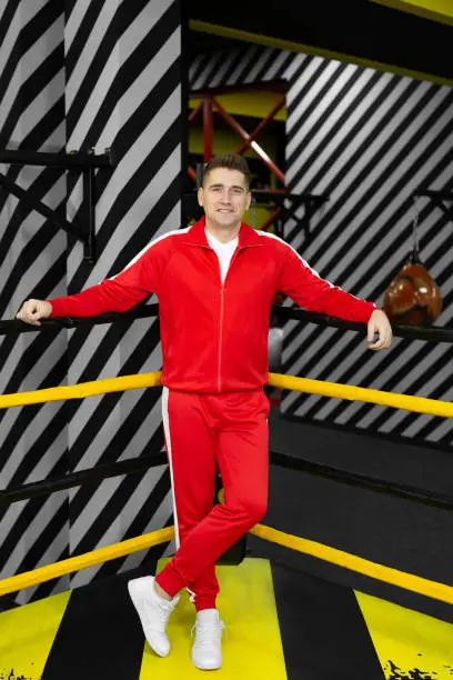 Photo of Man in a red tracksuit poses and has fun in the boxing ring