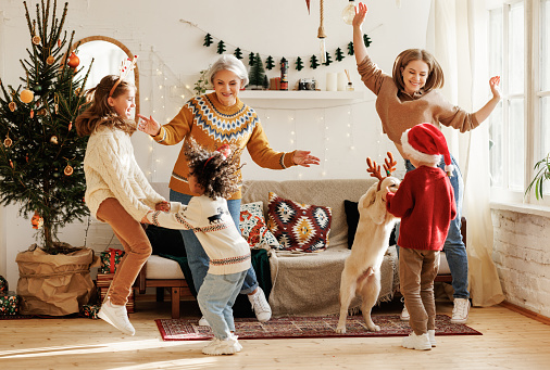 Feliz familia multirracial con tres hijos y golden retriever diviértete el día de Navidad en casa photo