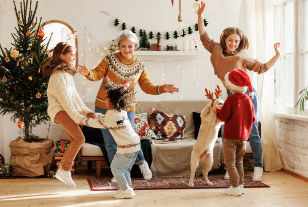 Happy multiracial family with three kids and golden retriever have fun on Christmas day at home Happy positive multiracial family with three kids and golden retriever have fun on Christmas day at home. Mother, grandmother and multiethnic children dance to New Year music during winter holidays merry christmas family stock pictures, royalty-free photos & images